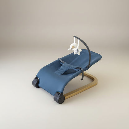 Momviacare blue fabric baby bouncer seat with wooden frame and toy bar, featuring a baby lying comfortably.